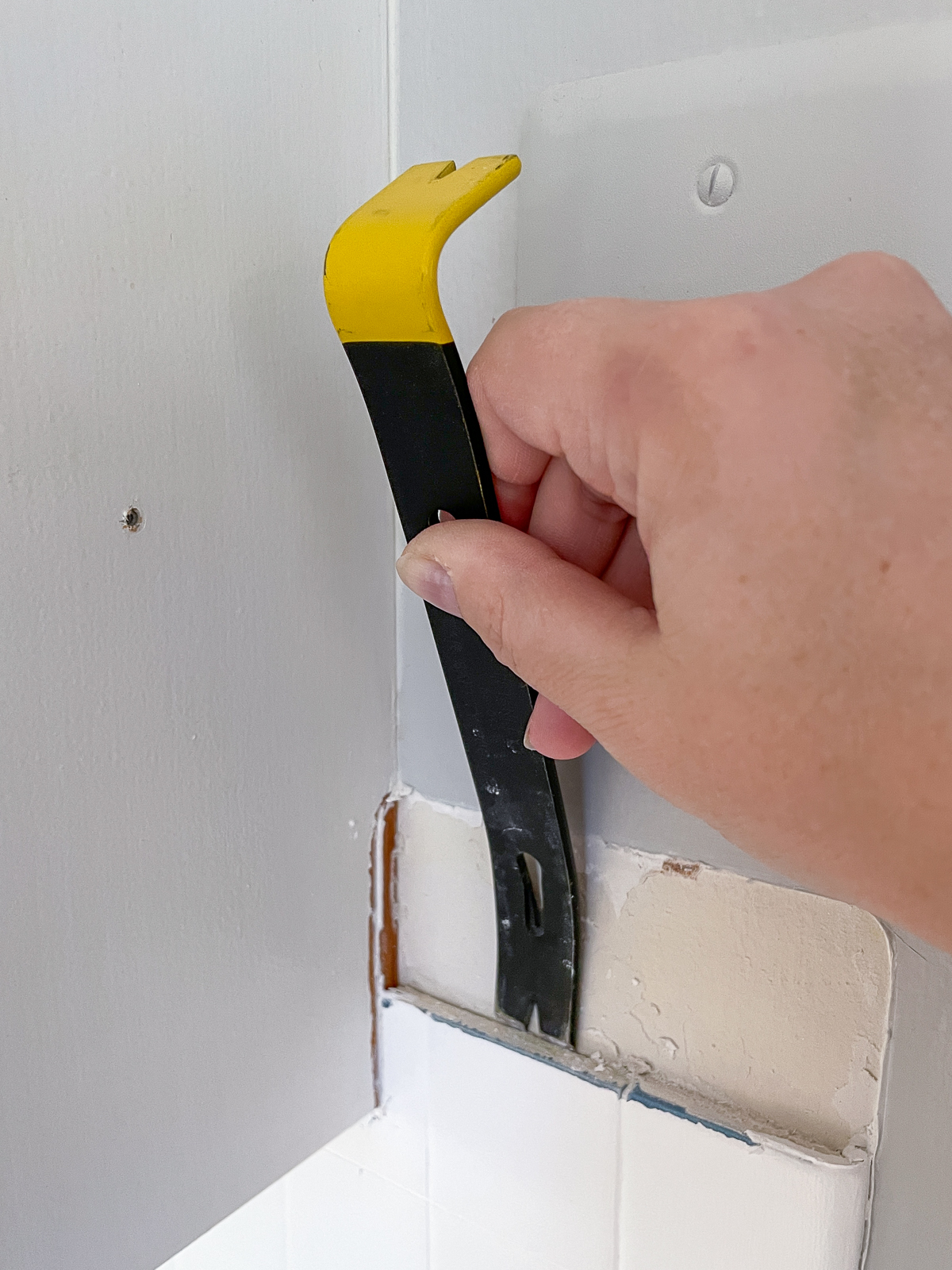 using a small pry bar to remove backsplash tile