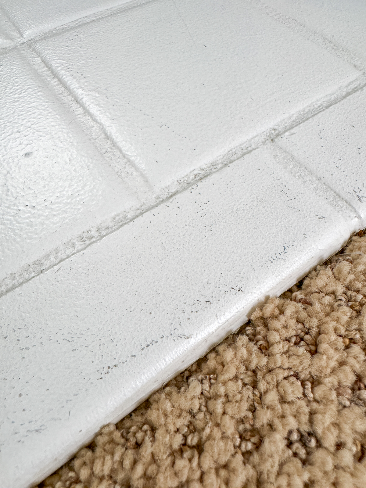 scuffs on painted tile floor where it meets the carpeted hallway