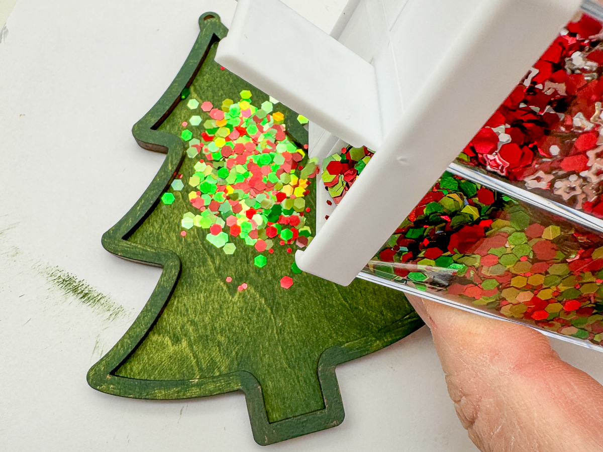 filling the inside of the laser cut Christmas ornament with red and green glitter