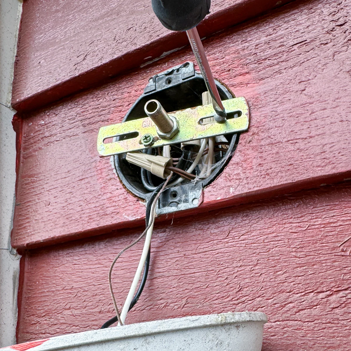 unscrewing the mounting bracket from the electrical box of an outdoor light fixture