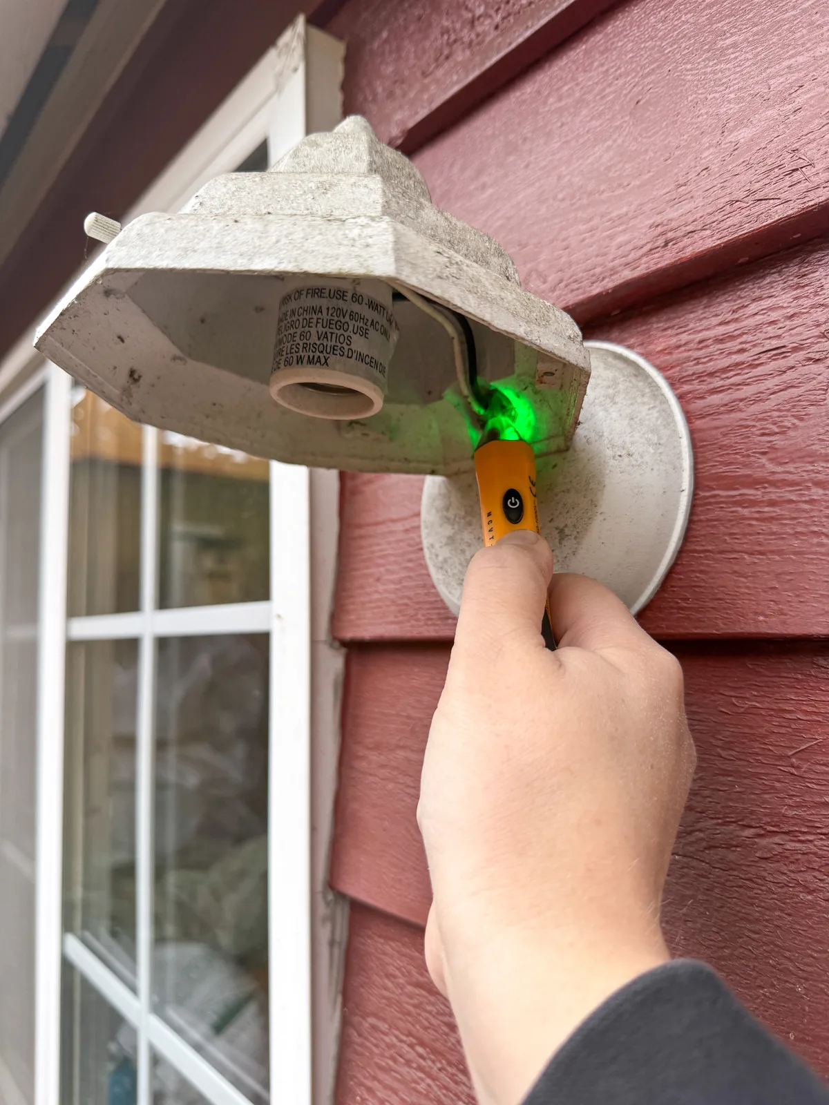 testing that the power to the outdoor light fixture is turned off with a voltage tester