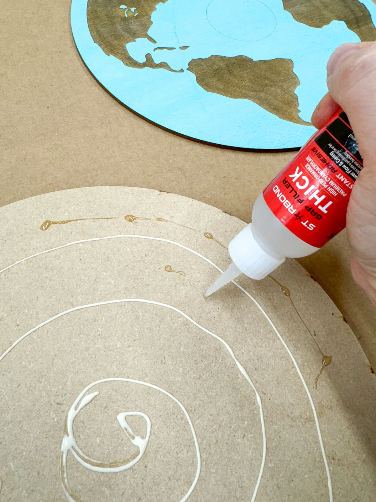 applying a combination of wood glue and CA glue to attach the engraved layer of the coin display to the backer