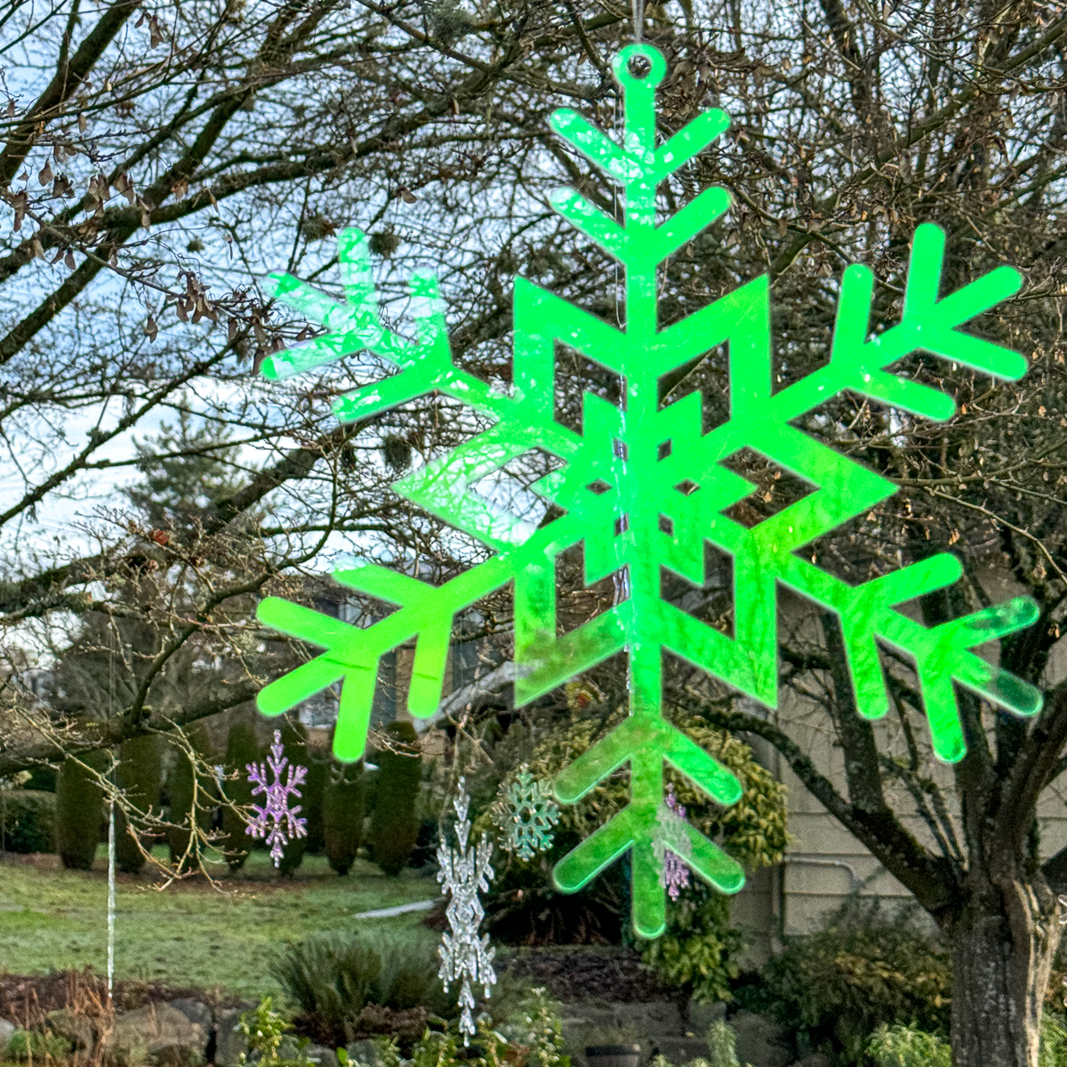 DIY outdoor snowflake decorations hanging in a tree in the front yard