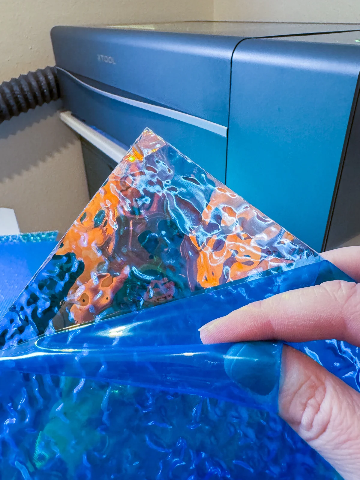 peeling blue plastic layer off iridescent ripple acrylic