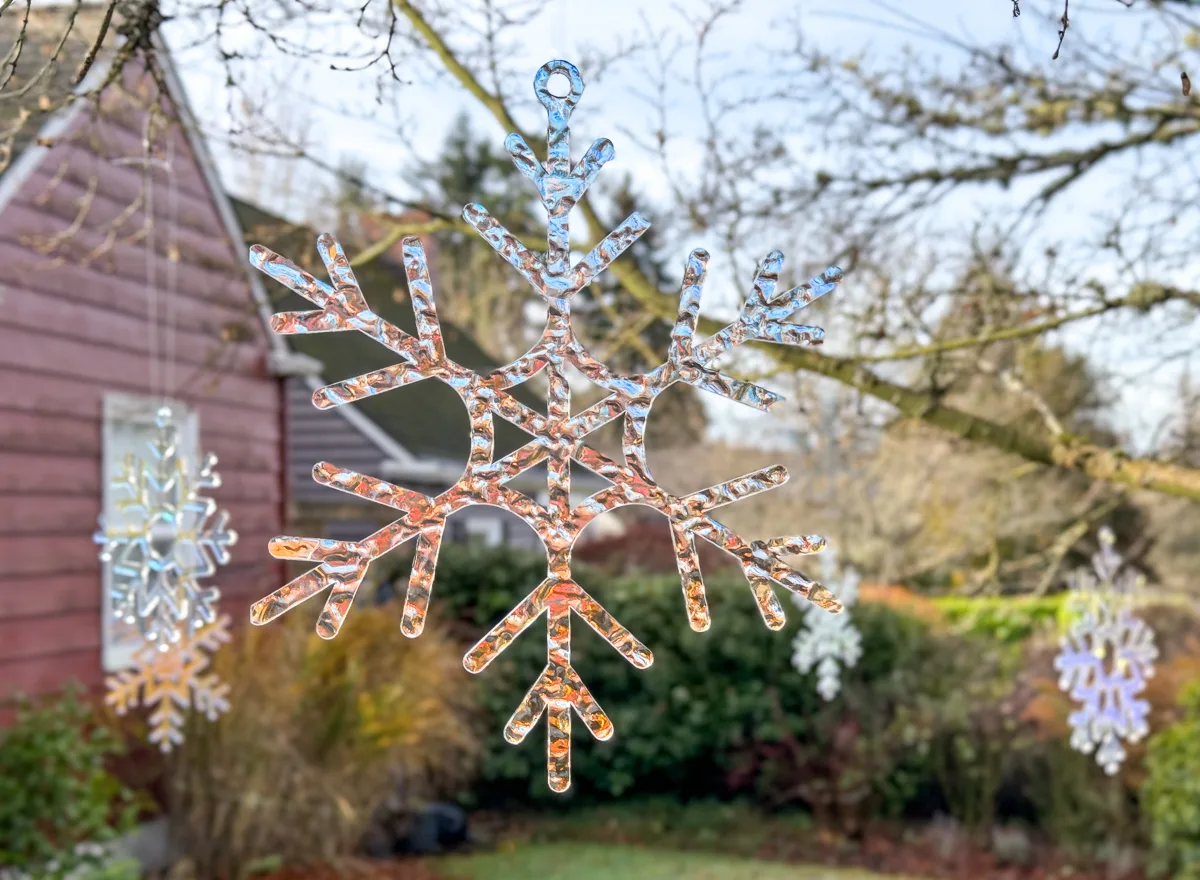 DIY snowflake decorations hanging from trees in yard