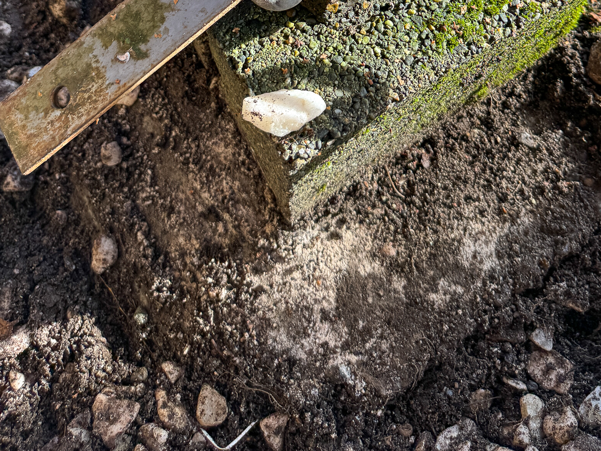 dirt around concrete fence post removed