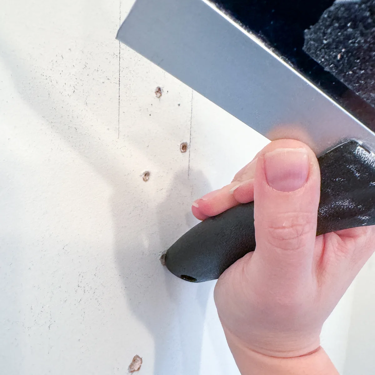 pressing in edges of hole in drywall to create a divot that is easier to fill smoothly