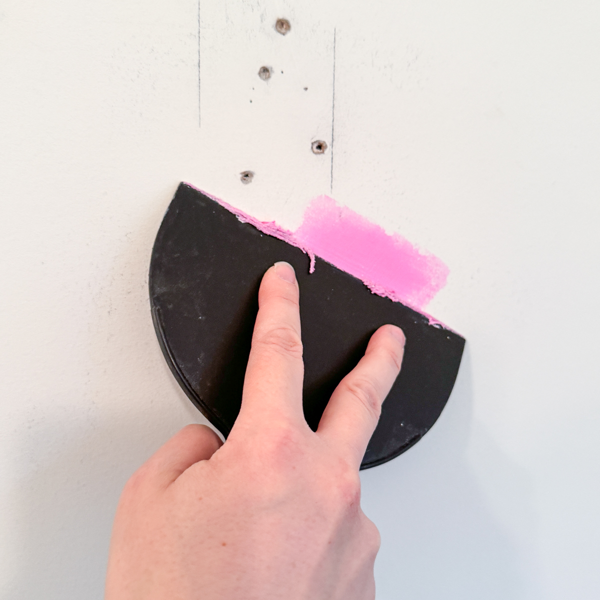 spreading spackle over a hole in drywall