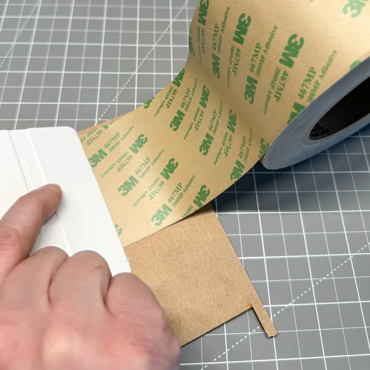 applying double sided adhesive to the back of the top layers of the puzzle before cutting out the pieces with the laser