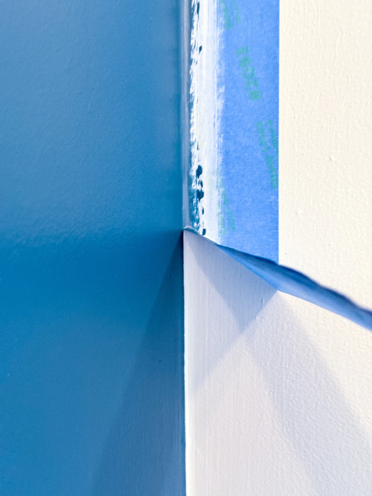 removing painter's tape along accent wall to reveal straight line at the corner