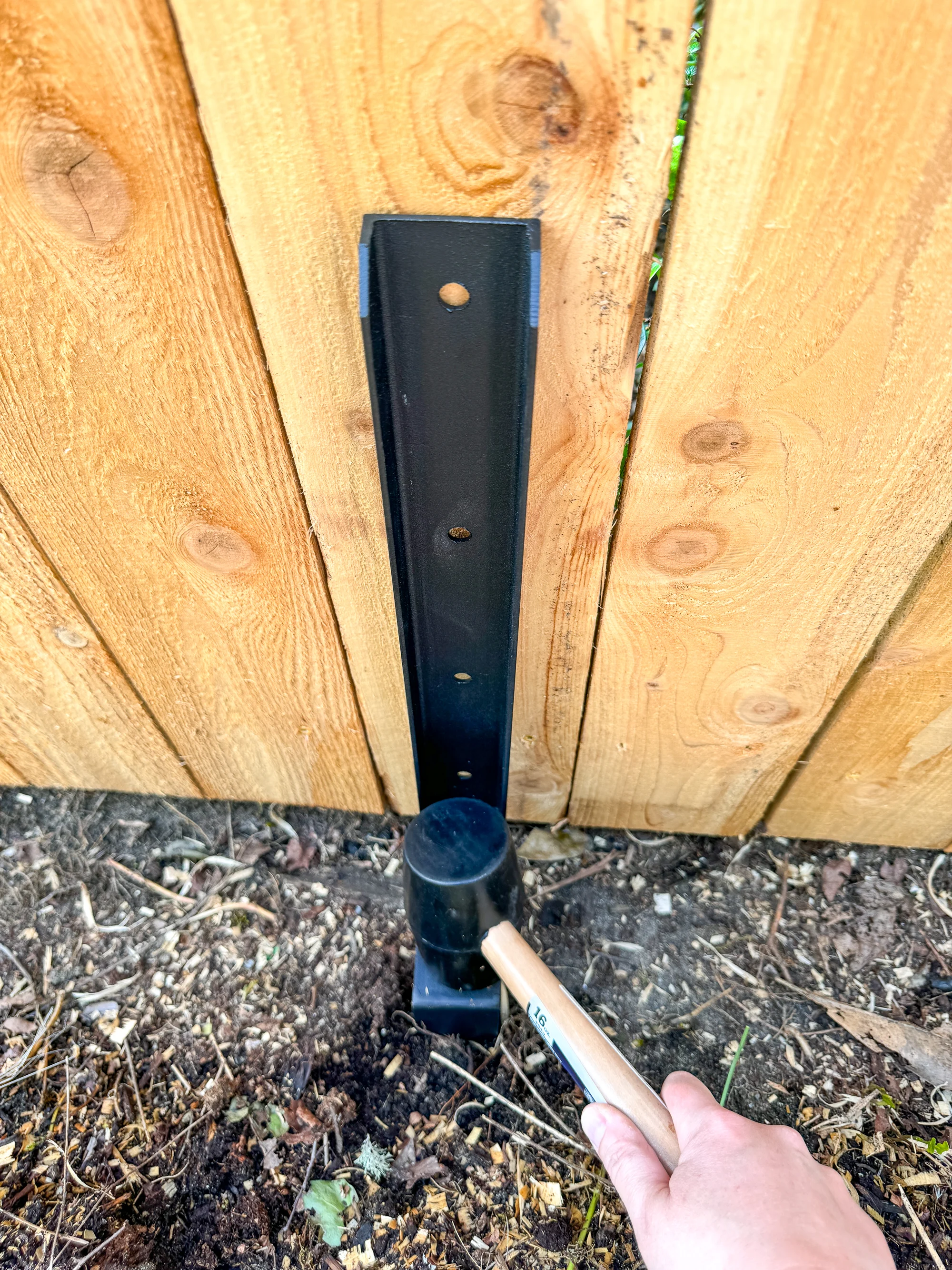 driving the fence repair stake into the ground with a rubber mallet