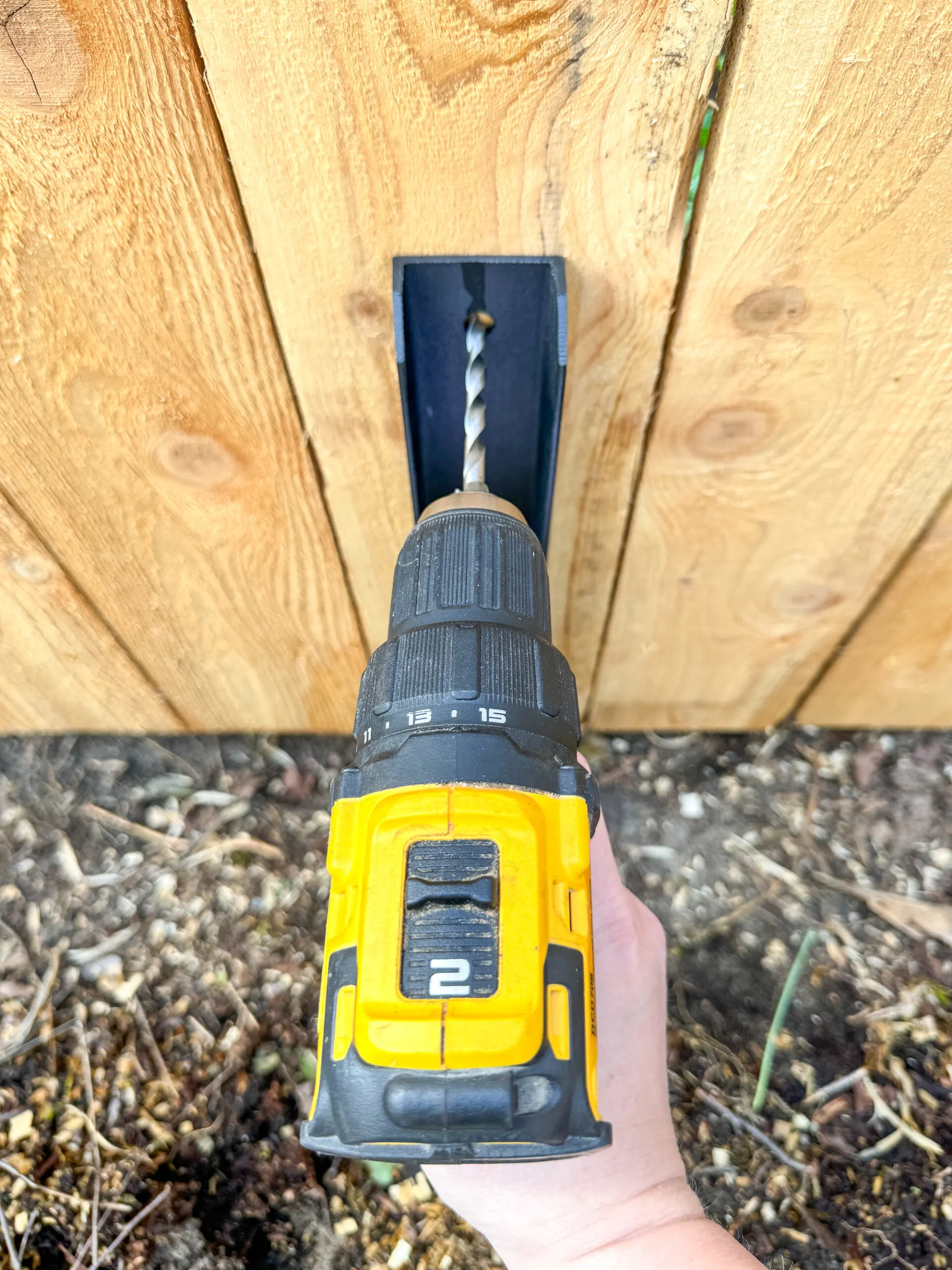 drilling pilot holes in fence post through fence repair bracket