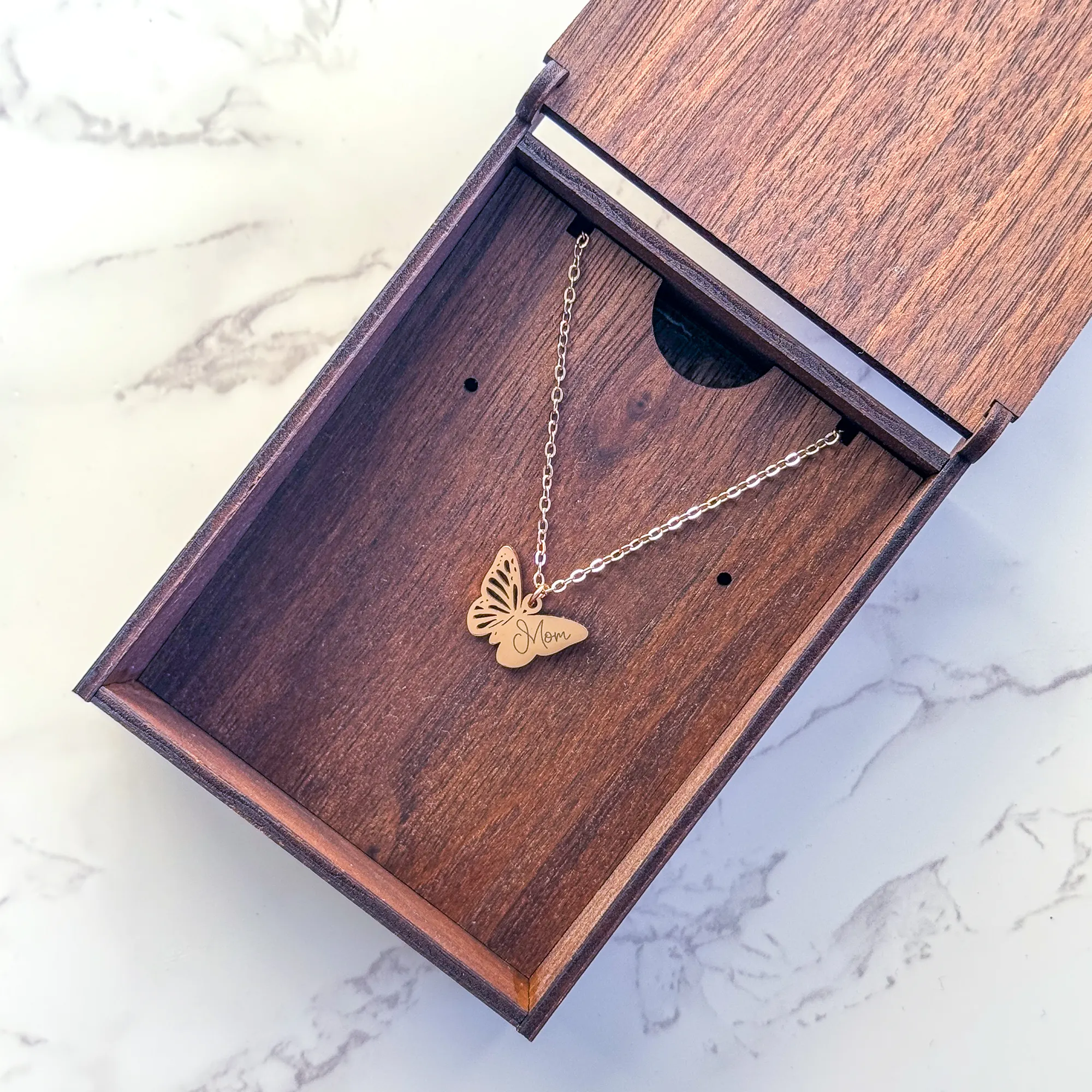 walnut wood jewelry box with butterfly engraved on top paired with rose gold butterfly pendant with "Mom" engraved on one wing stored inside