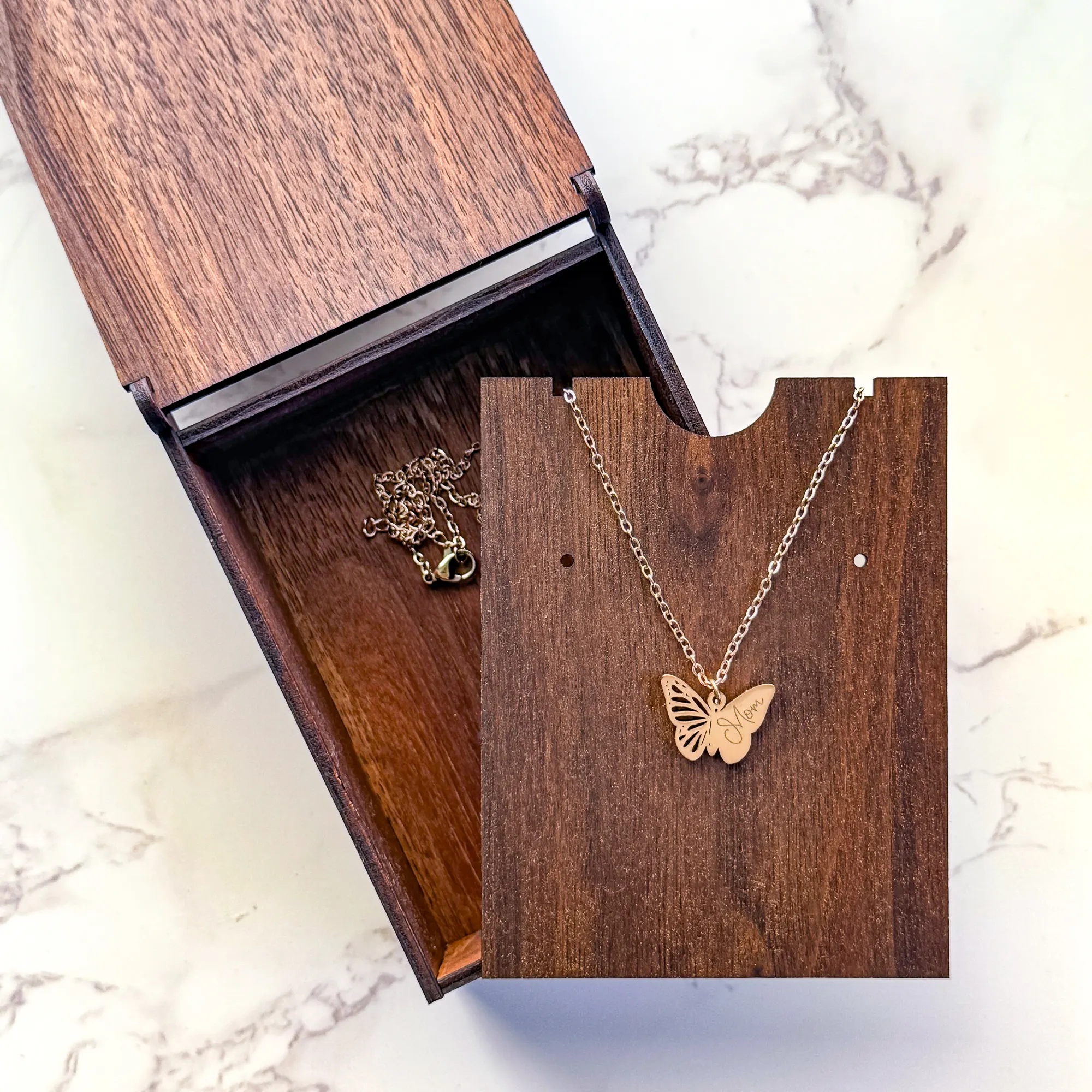 open walnut wood jewelry box with butterfly engraved on top paired with rose gold butterfly pendant with "Mom" engraved on one wing